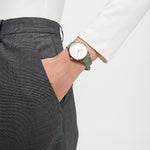 Eine Person in einer grauen Hose und einem weißen Oberteil trägt die Tamaris Armbanduhr - Stamped Flowers, Hand in der Tasche.