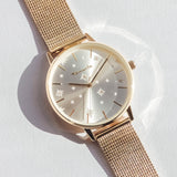 Eine Tamaris Armbanduhr - Shiny Stars mit einem goldenen Mesharmband und einem silbernen Sternenmuster auf der Vorderseite mit funkelnden Zirkoniasteinen, präsentiert auf einer weißen Oberfläche.