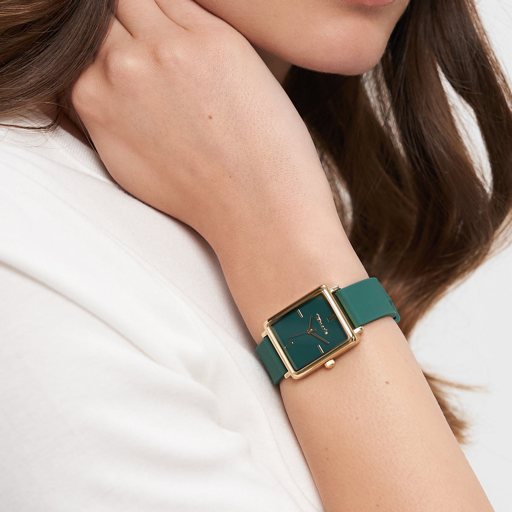 Eine Frau trägt die Tamaris Armbanduhr - The Silicon Square mit grünem Silikonarmband und goldenem quadratischem Zifferblatt und legt ihre Hand in den Nacken.