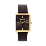 Die Tamaris Armbanduhr - The Silicon Square verfügt über ein rechteckiges, goldenes Gehäuse, ein schwarzes Zifferblatt mit minimalen Markierungen und ein elegantes Silikonband und bietet einen modernen, sportlichen Look der Marke Tamaris auf weißem Hintergrund.
