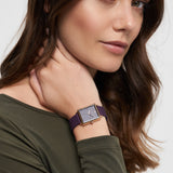 Frau mit langen braunen Haaren trägt ein olivgrünes Oberteil und eine Tamaris Armbanduhr - The Silicon Square von Tamaris und schaut in die Kamera.