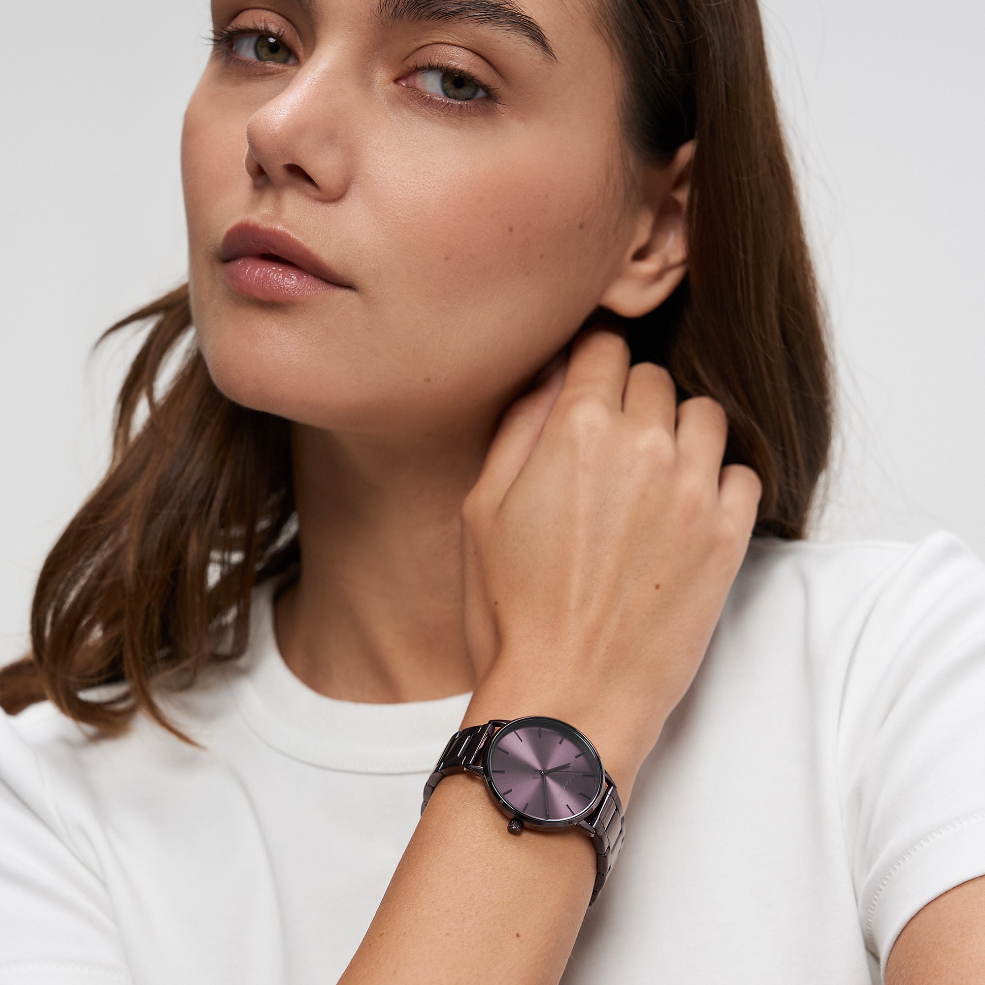 Frau in einem weißen Hemd, das ihren Hals berührt, trägt die Tamaris Armbanduhr - Everyday Hero mit lila Zifferblatt und schlichtem Edelstahlband.