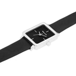 Detailansicht der Tamaris Tiny Watch mit schwarzem Lederarmband, Dornschließe und rechteckigem silberfarbenem Gehäuse